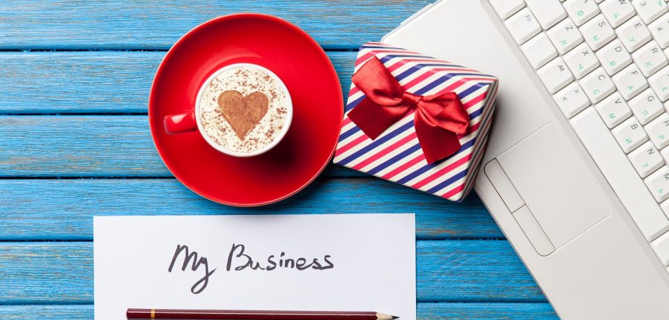 a sheet of the paper, a cup of coffee, gift, pencil and laptop lying on the blue wooden table